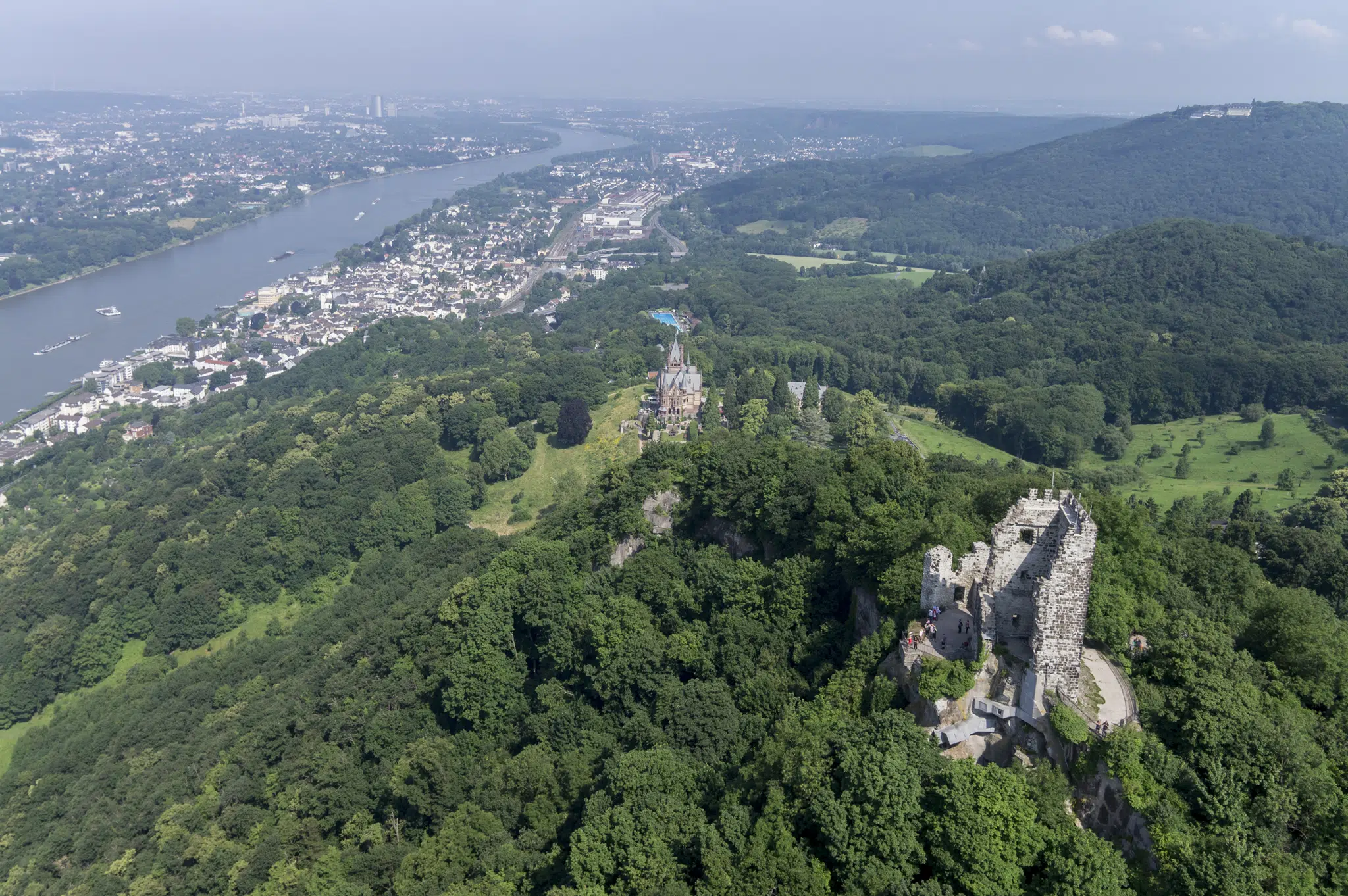 Ihr seht eine Luftaufnahme des Drachenfels mit Blick auf die Burgruine Drachenfels, den Rhein und Königswinter. JUFA Hotels bietet erlebnisreiche Städtetrips für die ganze Familie und den idealen Platz für Ihr Seminar.