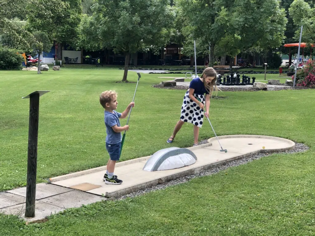 Ihr seht zwei Kinder beim Minigolf spielen im Freizeitpark Stubenbergsee.