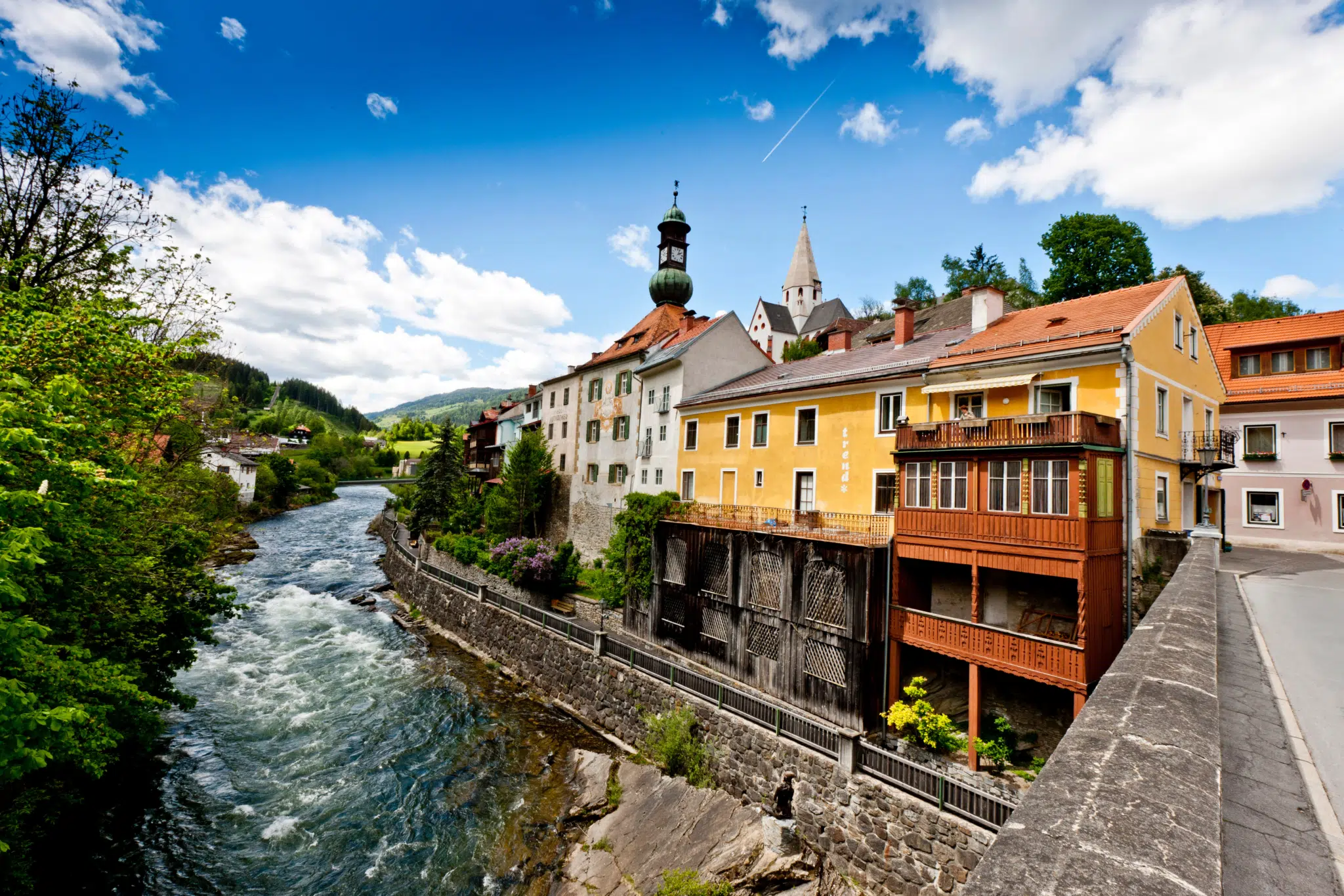 Ihr seht die Mur in Murau mit dem Rathaus und der Stadtpfarrkirche im Sommer. JUFA Hotels bietet erholsamen Familienurlaub und einen unvergesslichen Winter- und Wanderurlaub.