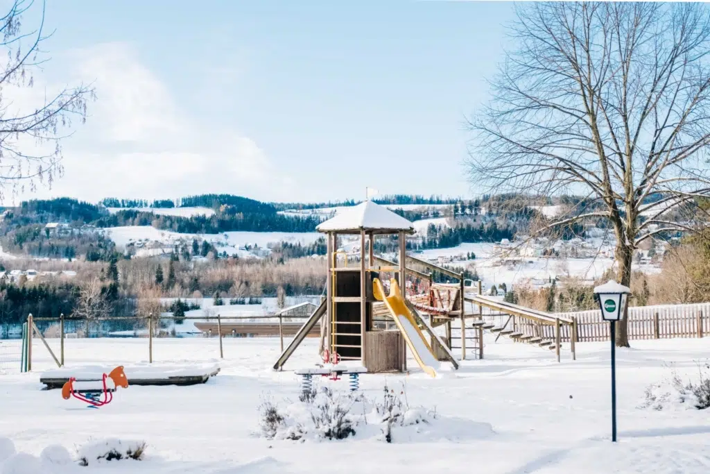 Ihr seht einen Outdoorspielbereich im JUFA Hotel Lipizzanerheimat*** im Winter. Der Ort für erholsamen Familienurlaub und einen unvergesslichen Winter- und Wanderurlaub.