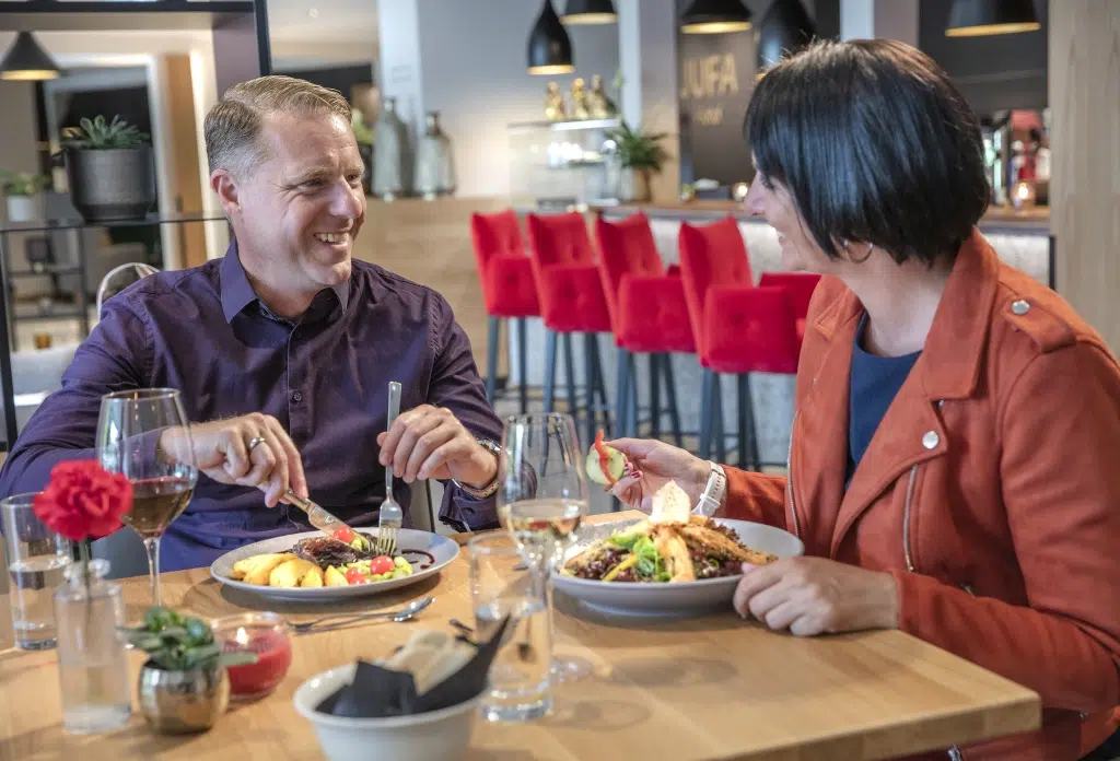 Ihr seht ein Paar im Restaurant im JUFA Hotel Salzburg City. Der Ort für erholsamen Familienurlaub und einen unvergesslichen Winter- und Wanderurlaub.