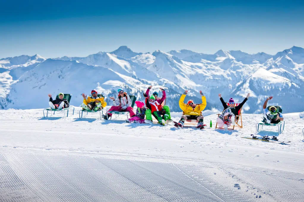 Ihr seht 8 Leute in Sesseln auf der Planneralm chillen. Die schneebedeckten Berge im Hintergrund.