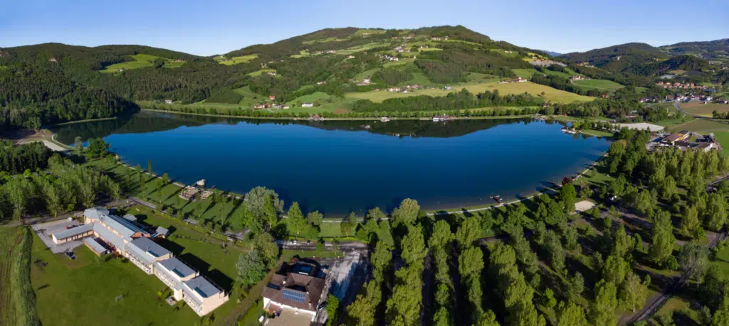 Ihr seht ein Panoramabild vom Stubenbergsee mit Umgebung in der Oststeiermark mit dem JUFA Hotel Stubenbergsee*** direkt am Seeufer.