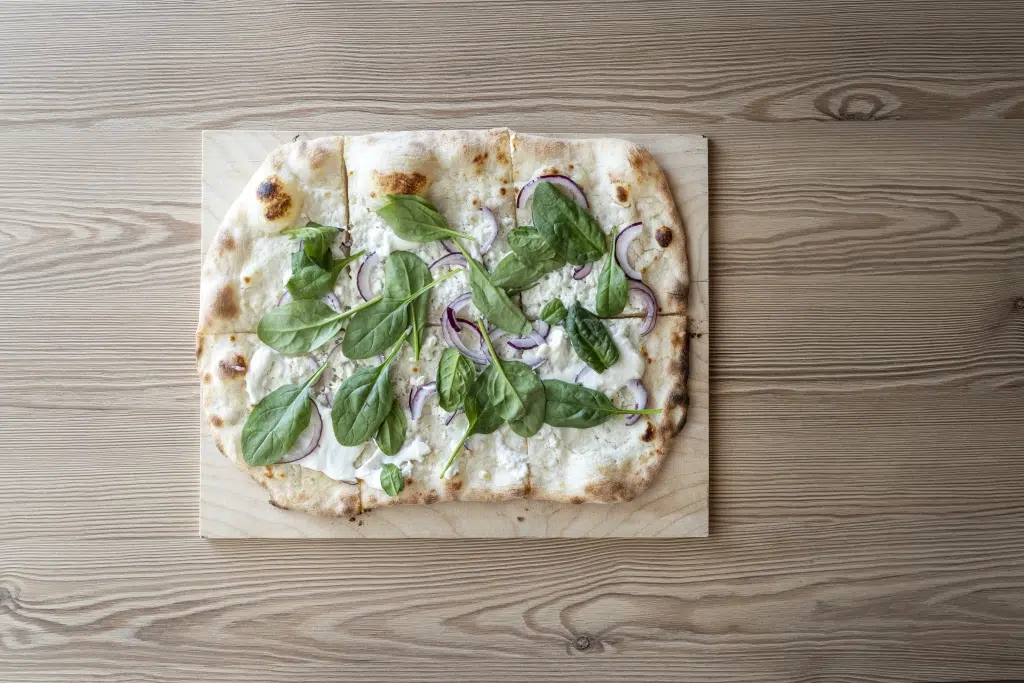 Sie sehen eine Spinatpizza in der Pizzeria La Trattoria. Das JUFA Hotel Wipptal ist der ideale Ausgangspunkt für einen erlebnisreichen Urlaub.