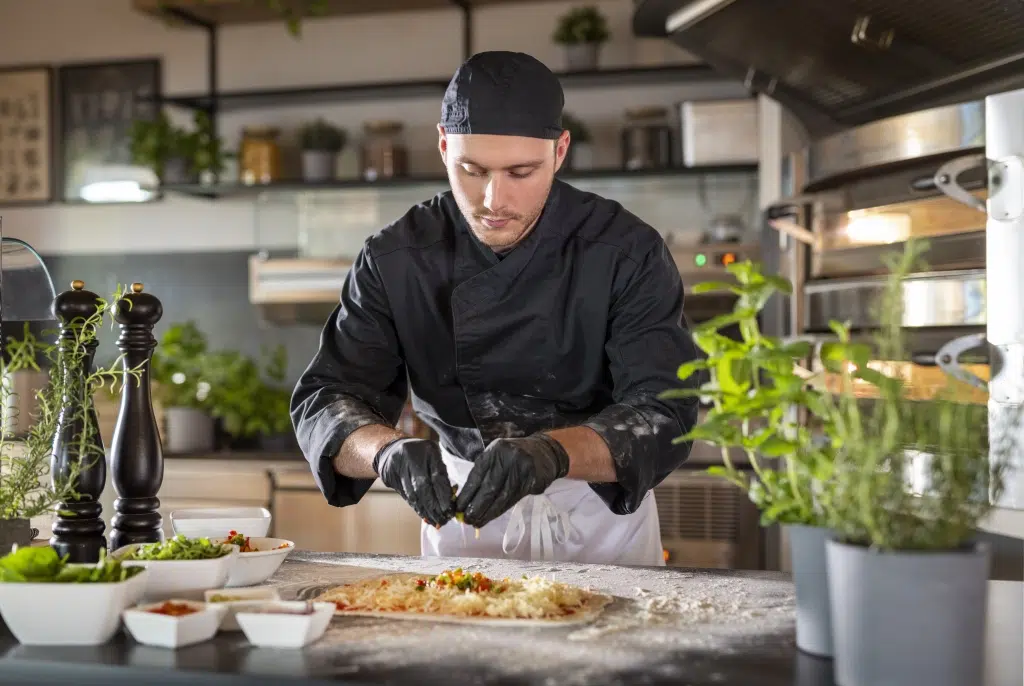 Sie sehen einen Pizzaiolo bei der Zubereitung von Pizzen in der Pizzeria la Trattoria im Wipptal. Das JUFA Hotel Wipptal ist der ideale Ausgangspunkt für einen erlebnisreichen Urlaub im Süden Innsbrucks.