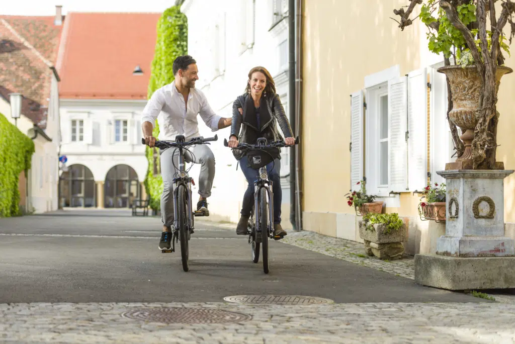 Ihr seht einen Mann und eine Frau beim Radfahren in der Altstadt von Bad Radkersburg in der Nähe vom JUFA Hotel Bad Radkersburg.