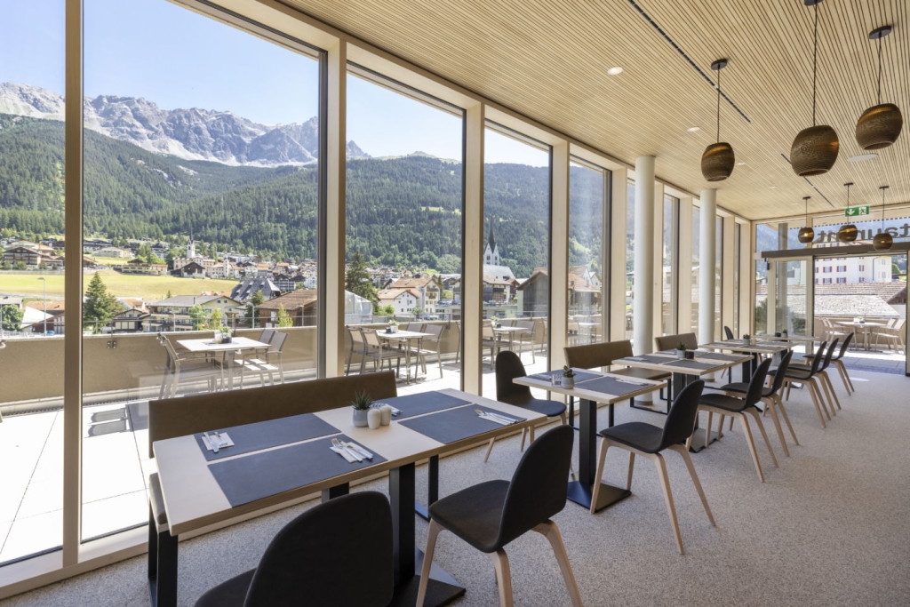 Sie sehen das Restaurant mit Blick auf die Terrasse des JUFA Hotel Savognin***s.