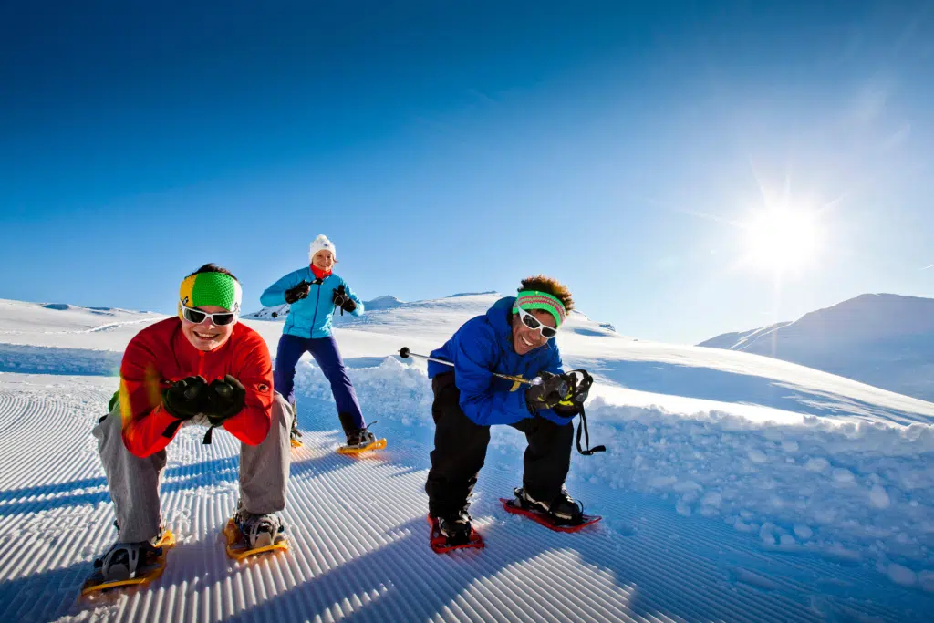 Ihr seht zwei Männer und eine Frau mit Schneeschuhen auf der Piste.