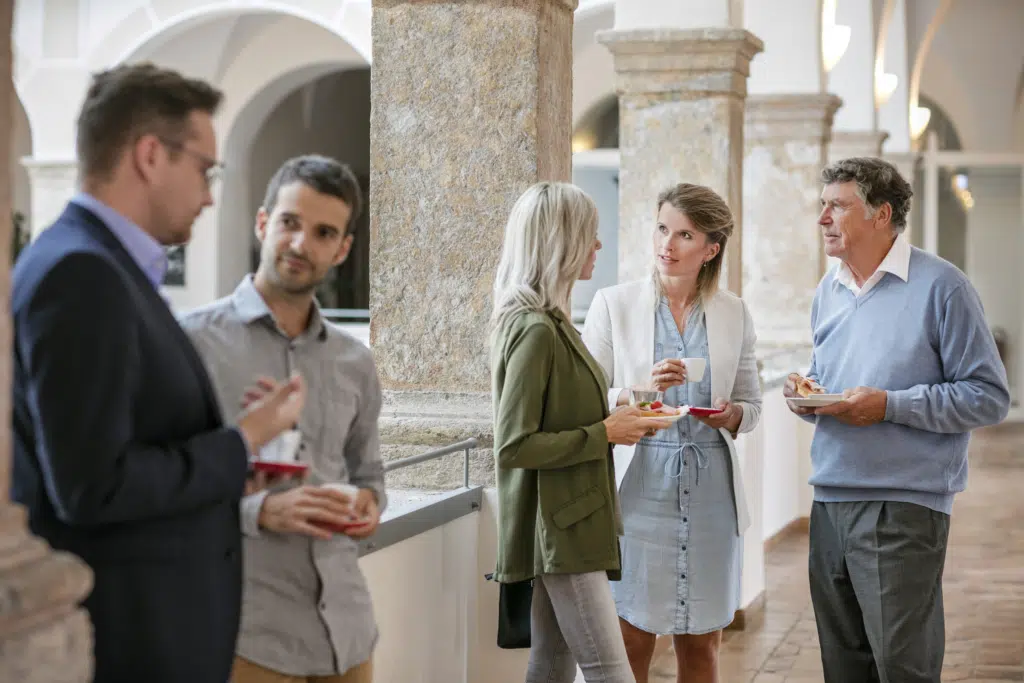 Ihr seht Seminarteilnehmer*innen bei einer Pause am Gang im JUFA Hotel Schloss Röthelstein/Admont***. Der Ort für märchenhafte Hochzeiten und erfolgreiche und kreative Seminare.