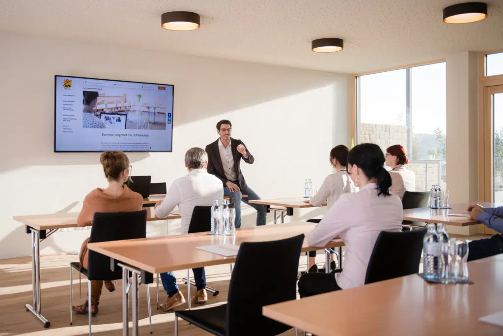 Ihr seht einen gut ausgestatteten Seminarraum im JUFA Hotel Neutal – Landerlebnis mit Seminargetränken. JUFA Hotels bietet den Ort für erfolgreiche und kreative Seminare in abwechslungsreichen Regionen.