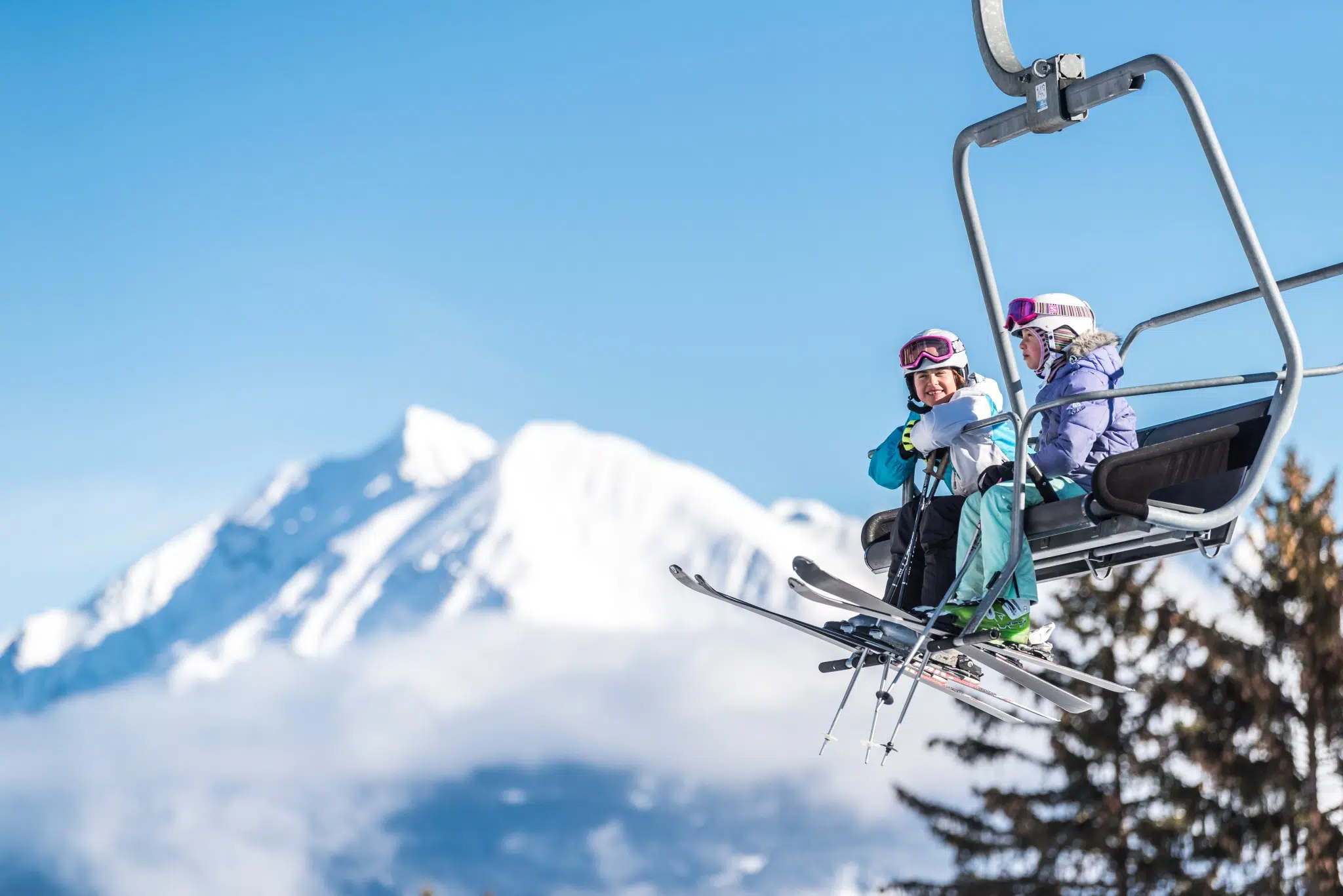 Sie sehen zwei Personen am Sessellift in Savognin im Winter. JUFA Hotels bietet erholsamen Familienurlaub und einen unvergesslichen Winterurlaub.