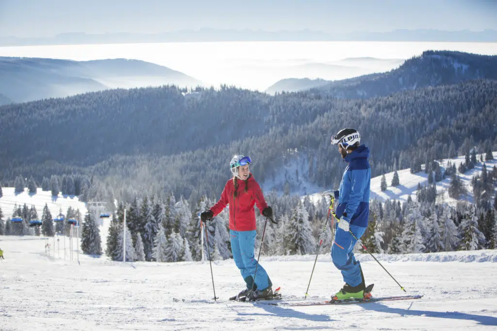 Ihr seht zwei Personen beim Skifahren am Feldberg im Schwarzwald.