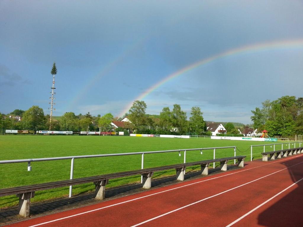 Ihr seht die Hallen- und Rasenplätze vom SpVgg Ederheim 1949 e.V. mit einem Regenbogen, die von Gästen des JUFA Hotels Nördlingen genutzt werden können.