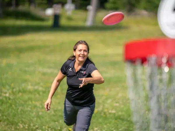 Ihr seht eine Frau, die auf den Nockbergen Disc Golf spielt.