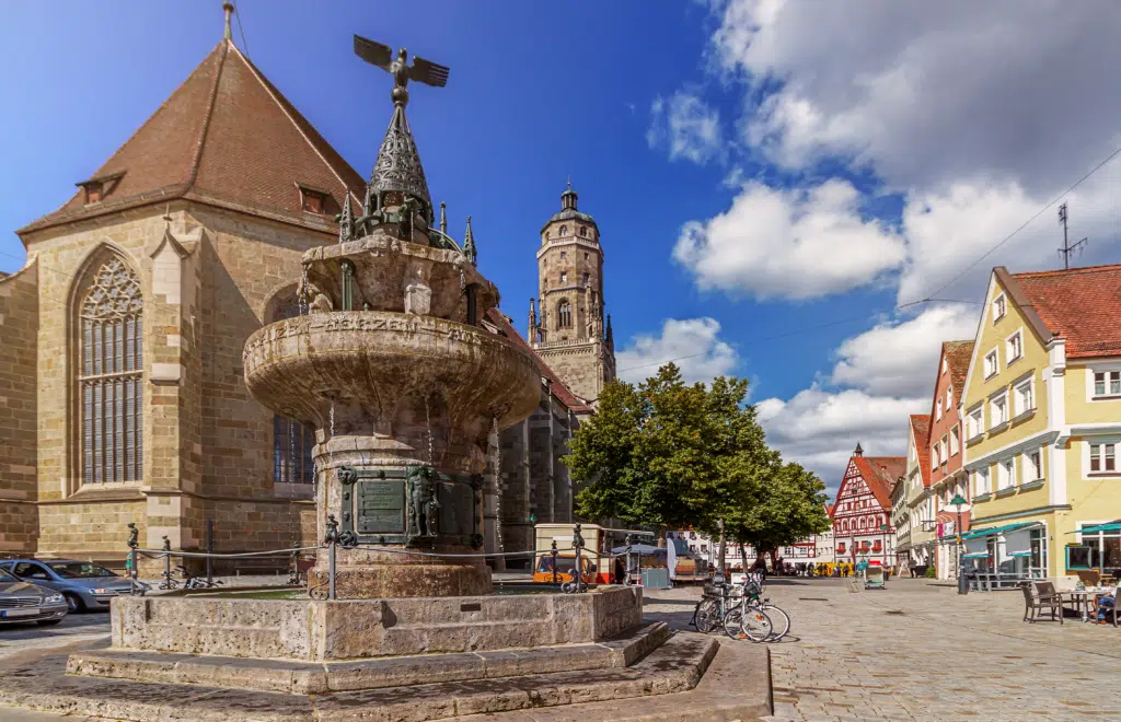 Ihr seht das Stadtzentrum von Nördlingen mit einem Brunnen im Sommer. JUFA Hotels bietet erholsamen Familienurlaub und einen unvergesslichen Winter- und Wanderurlaub.