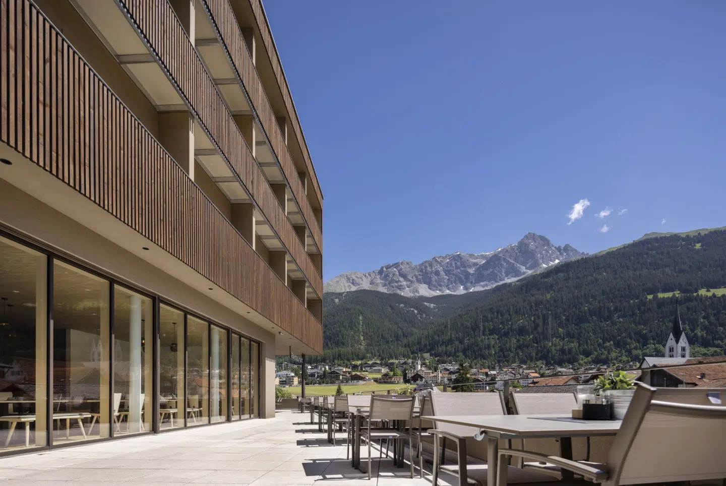 Sie sehen die Terrasse des JUFA Hotel Savognin***s mit Blick auf das Bergpanorama rund um Savognin.