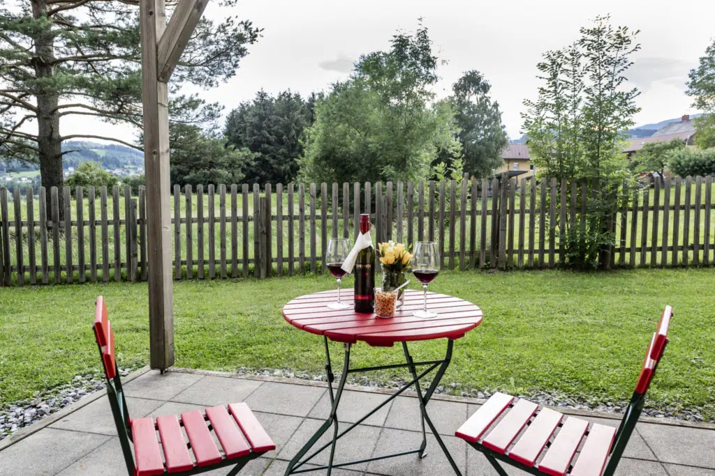 Ihr seht eine Terrasse in einem Familienzimmer Typ Family and Friends 4 Plus im JUFA Hotel Maria Lankowitz mit Wein. JUFA Hotels bietet tollen Sommerurlaub an schönen Seen für die ganze Familie.