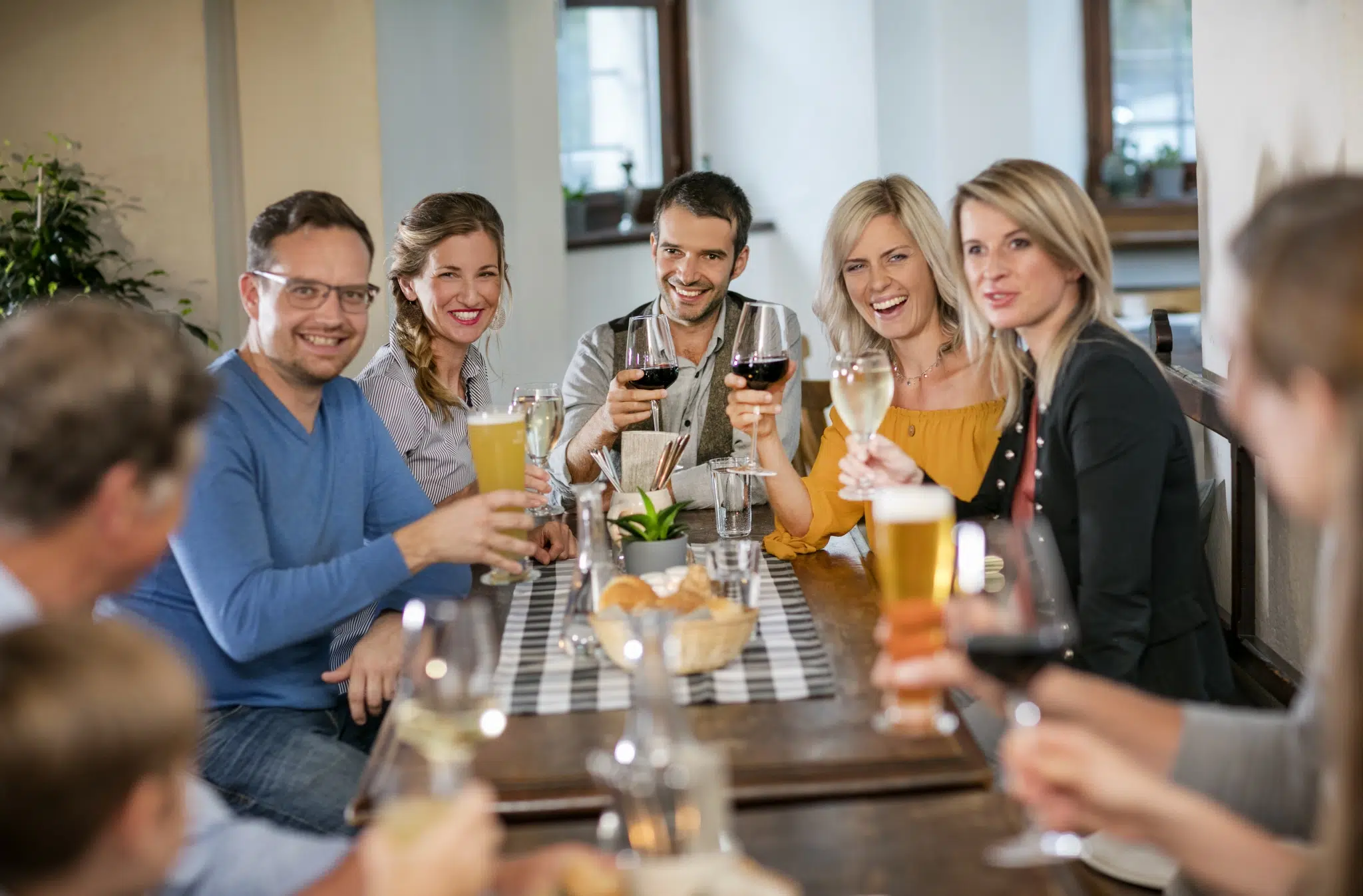 Ihr seht Gäste in der Rauchkuchl des JUFA Hotel Schloss Röthelstein*** am Tisch sitzen und mit Getränken anstoßen. JUFA Hotels bietet den Ort für märchenhafte Hochzeiten und erfolgreiche und kreative Seminare.