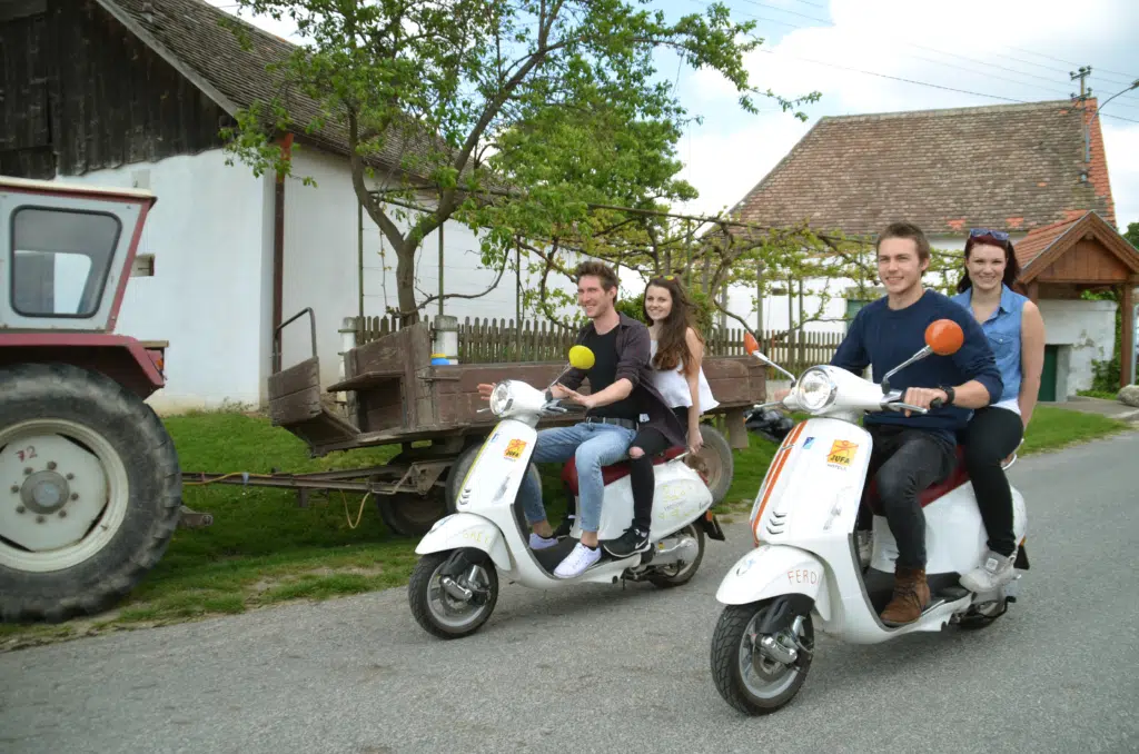 Pärchen beim Vespafahren im Weinviertel in der Nähe vom JUFA Weinviertel - Hotel in der Eselsmühle. Der Ort für kinderfreundlichen und erlebnisreichen Urlaub für die ganze Familie.