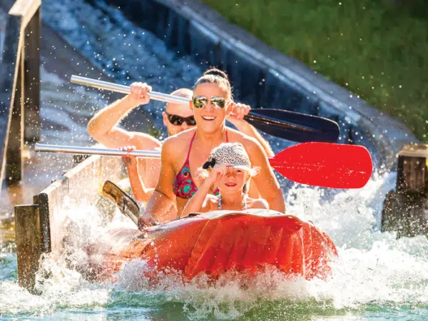 Ihr seht eine lachende Familie in einem Wasser- und Erlebnisspielpark.