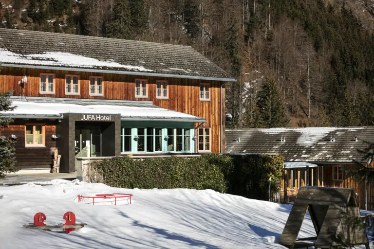 Ihr seht das JUFA Hotel Eisenerz und den Eingangsbereich von Außen im Winter. Der Ort für erholsamen Familienurlaub und einen unvergesslichen Winter- und Wanderurlaub.