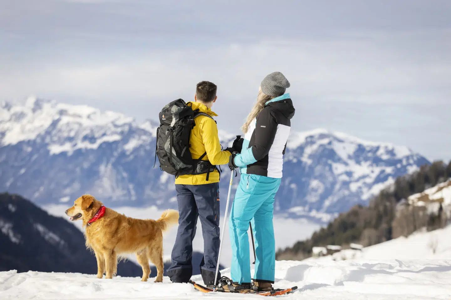 Sie sehen ein Paar mit Hund den Panoramablick ins Tal genießen. Das JUFA Hotel Laterns – Klangholzhus ist der perfekte Ort für einen abwechslungsreichen Winterurlaub für die ganze Familie mit erholsamen Urlaubstagen.