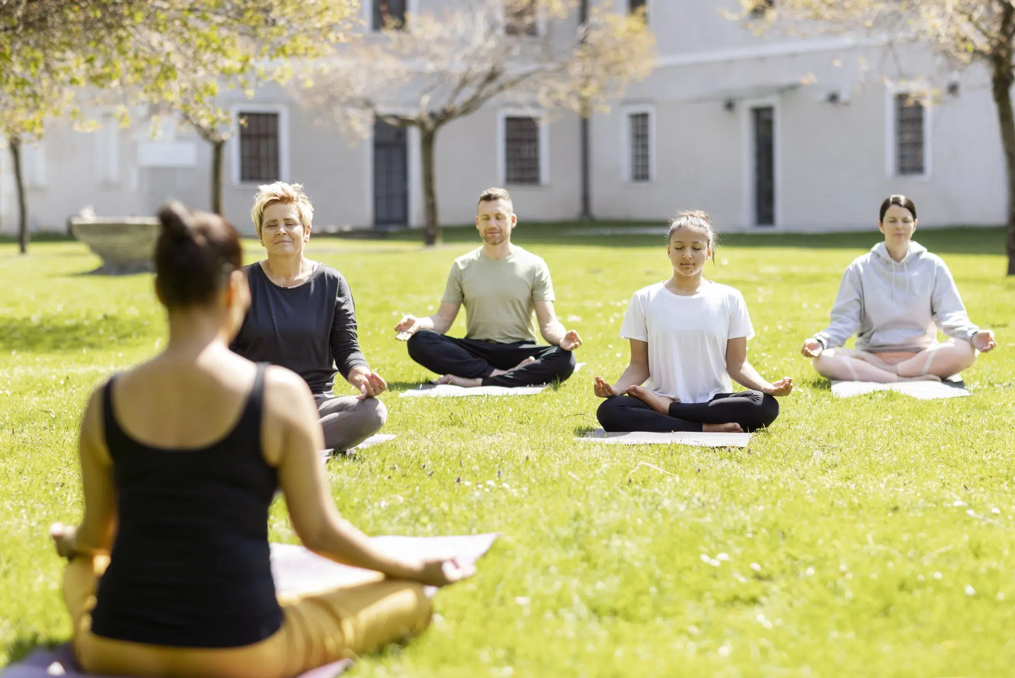 Ihr seht eine Gruppe bei der Meditation im Klostergarten des JUFA Hotel Stift Gurk****. Der Ort für erholsamen Thermen- und entspannten Wellnessurlaub für die ganze Familie.