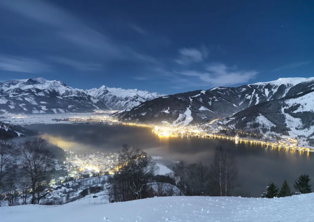 Zell am See in der Nacht im Winter im Salzburgerland. JUFA Hotels bietet erholsamen Familienurlaub und einen unvergesslichen Winterurlaub.