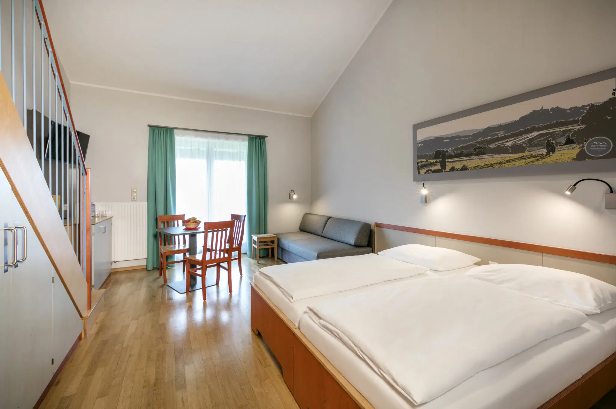 Ihr seht ein Zimmer FF3 mit Bett und Treppe im JUFA Hotel Vulkanland – Sport-Resort. Der Ort für erfolgreiches Training in ungezwungener Atmosphäre für Vereine und Teams.