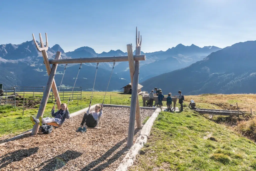 Ihr seht Kinder am Spielplatz in den Bergen von Savognin