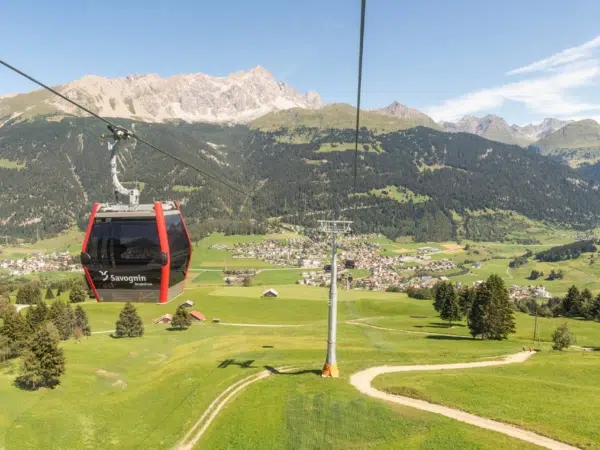 Ihr seht die Bergbahnen Savognin im Sommer über die Stadt Savognin schweben