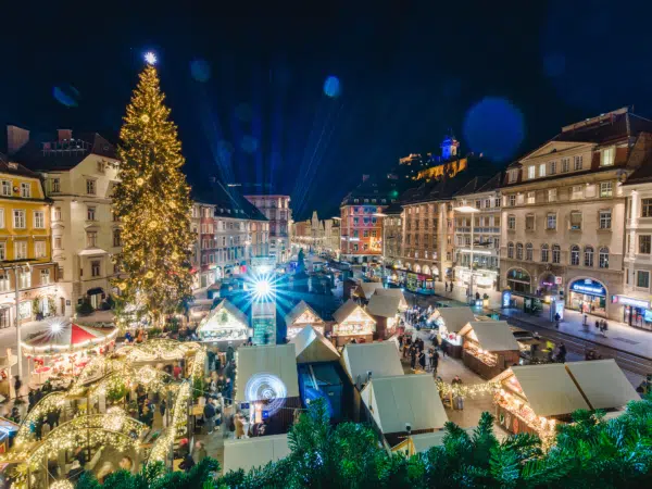 Ihr seht den Adventmarkt am Grazer Hauptplatz mit dem Christbaum von oben bei Nacht.