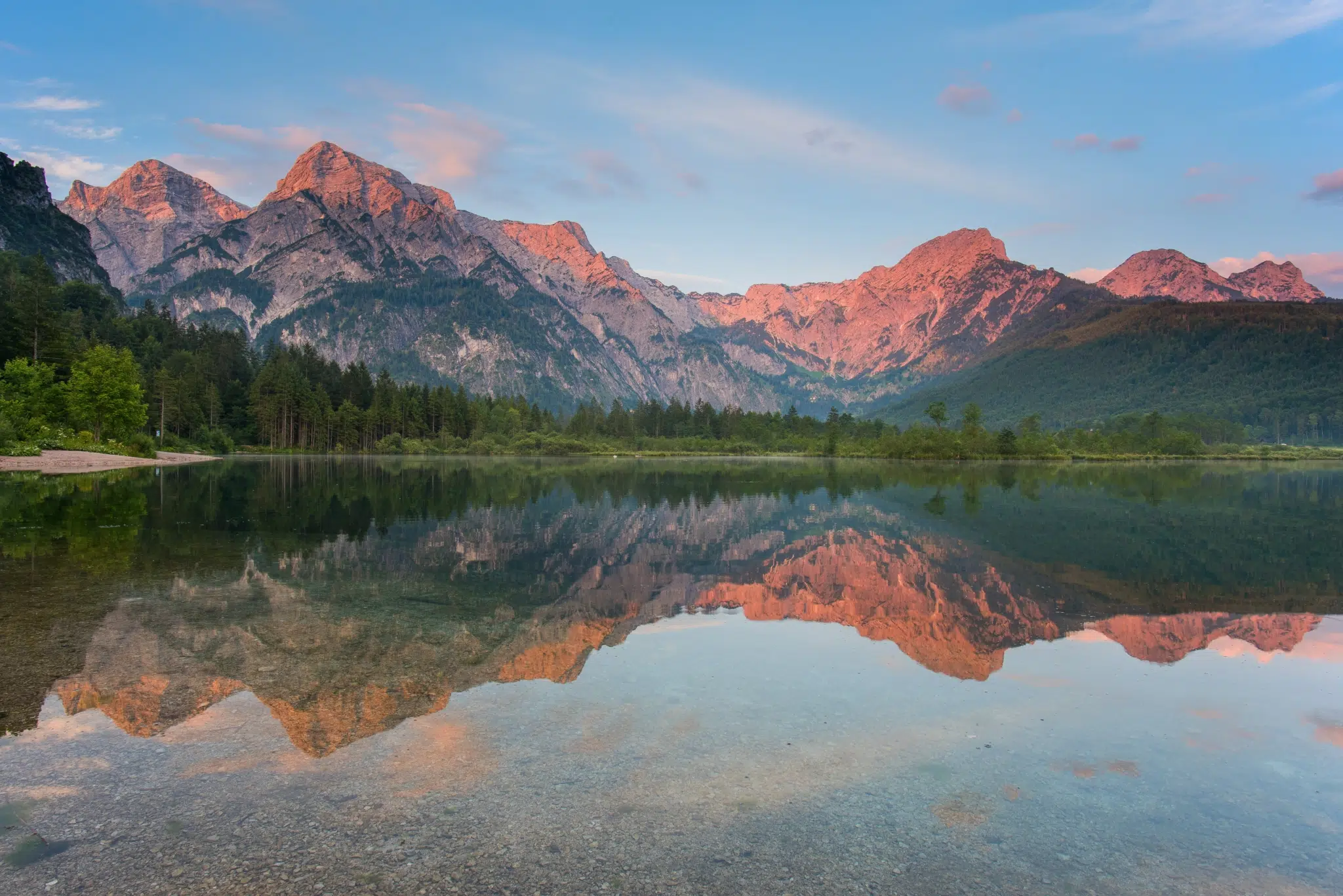 Ihr seht ein Panorama des Toten Gebirges hinter dem Almsee in Oberösterreich im Abendlicht.