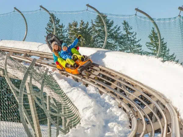 Ihr seht zwei Kinder im Winter auf der Sommerrodelbahn der Alpsee Bergwelt.