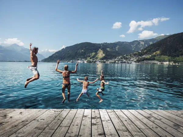 Ihr seht eine Familie, die vom Steg in den Zeller See springt im Sommer.