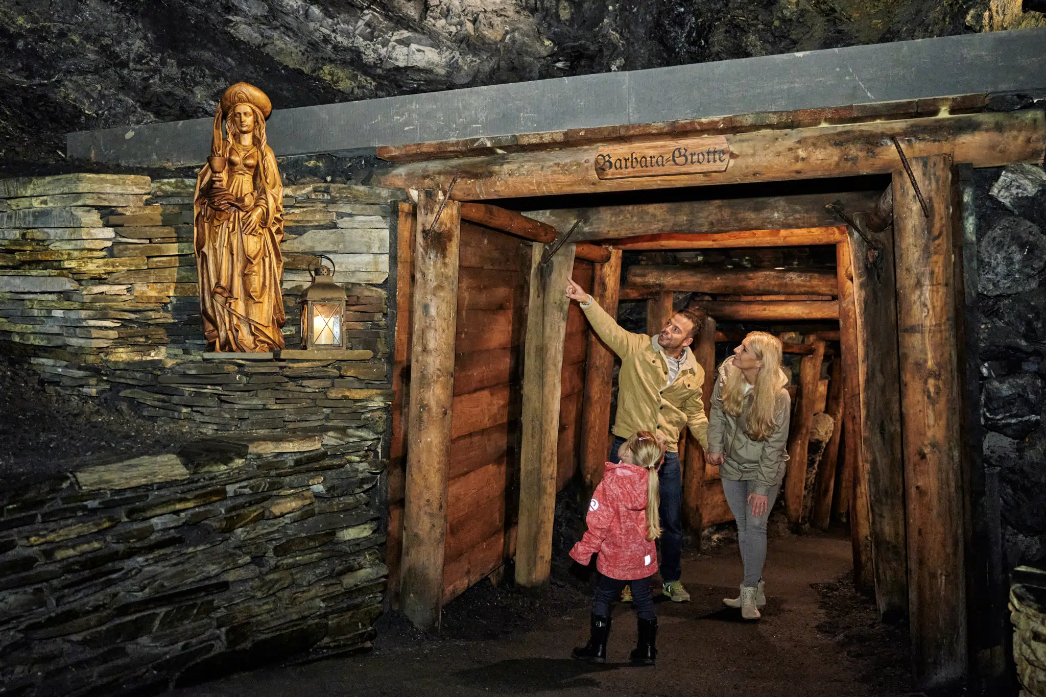 Ihr seht den Barbarastollen der Feengrotten mit einer Familie die voller Vorfreude durch den Stollen geht.