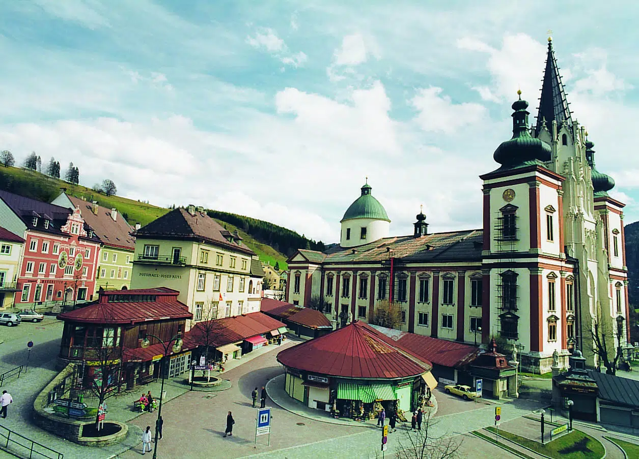 Ihr seht die Basilika Mariazell mit Dorfplatz in Mariazell in der Steiermark in der Nähe von JUFA Hotels. Der Ort für erholsamen Familienurlaub und einen unvergesslichen Winter- und Wanderurlaub.