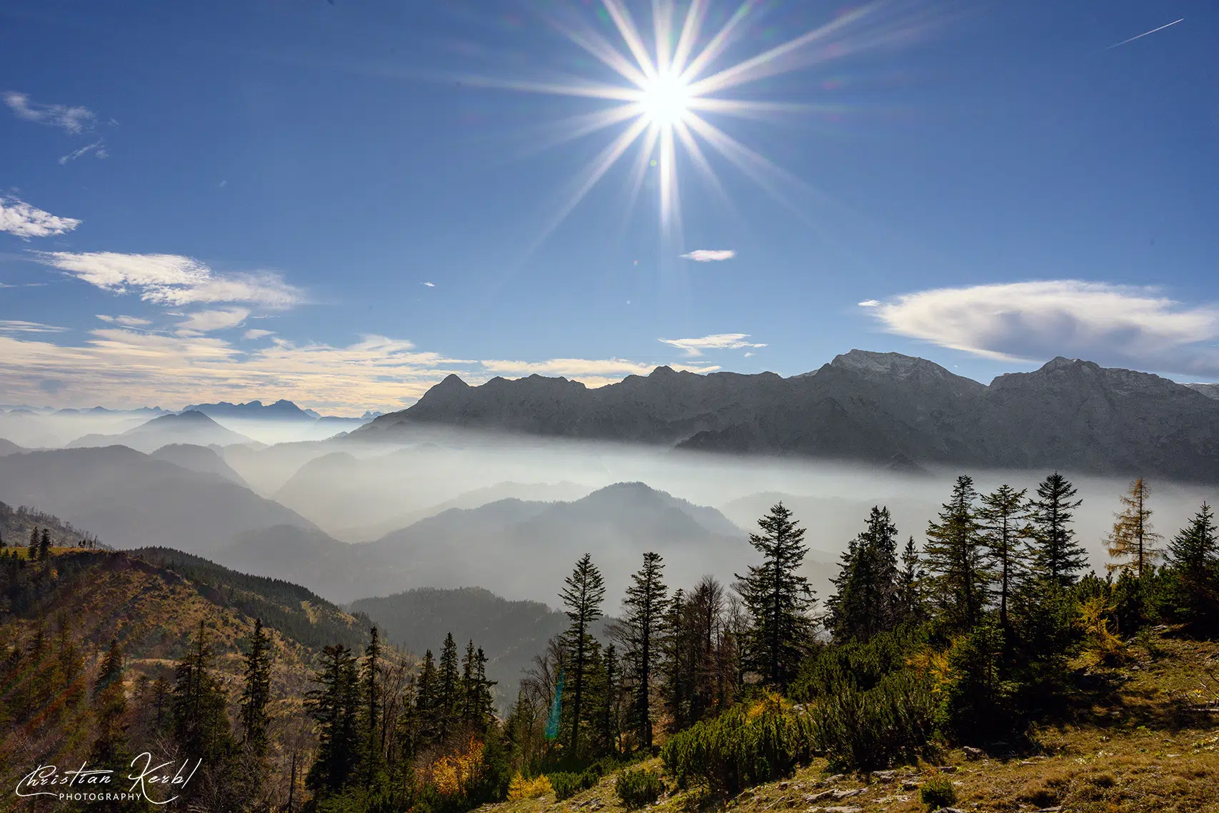 Ihr seht den Blick vom Kasberg auf das Tote Gebirge in Oberösterreich im Herbst mit Nebel und Sonne.