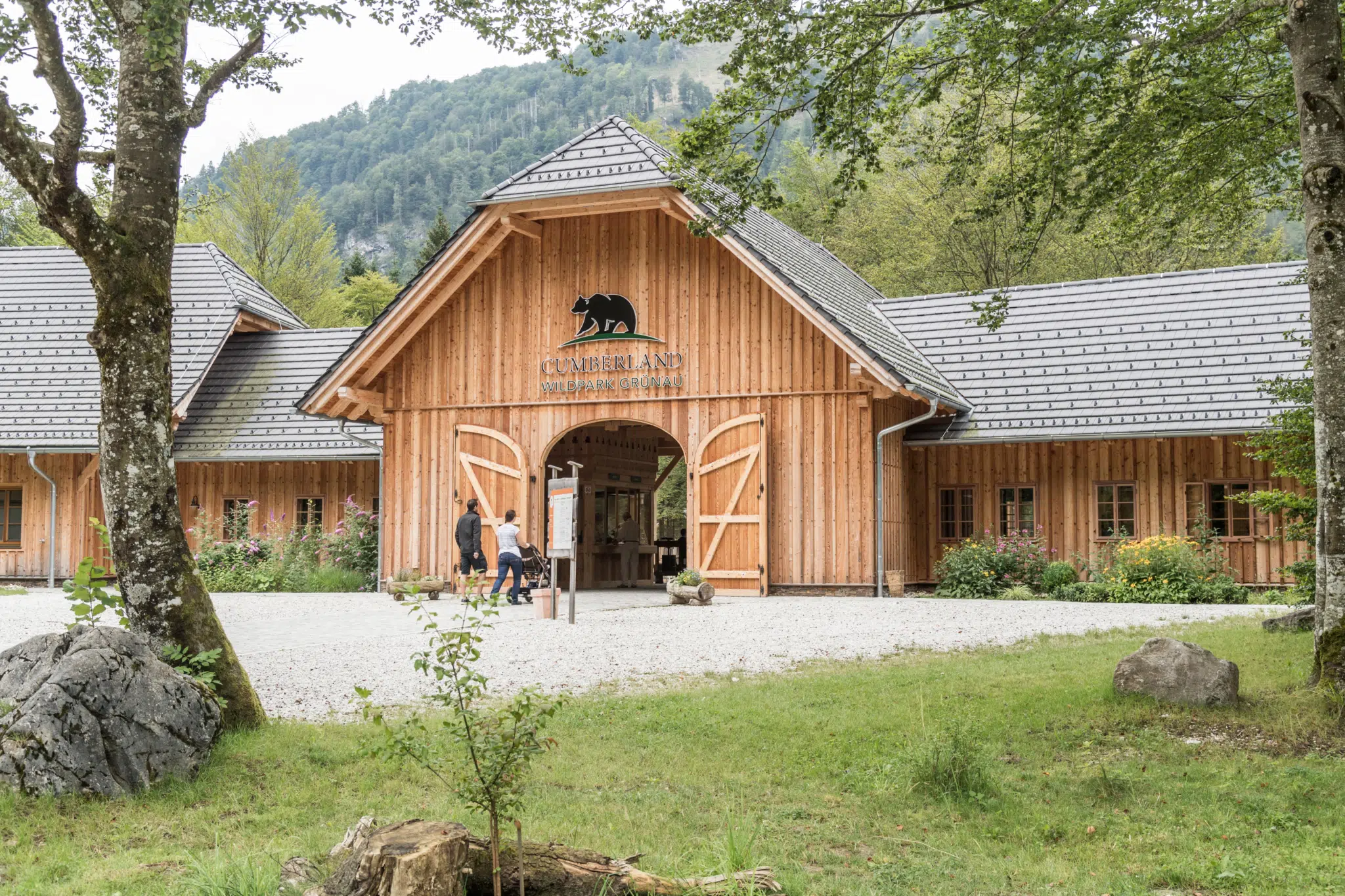 Familie geht auf den Eingang des Cumberland Wildparks Grünau zu. JUFA Hotels bietet euch den Ort für erlebnisreichen Natururlaub für die ganze Familie.