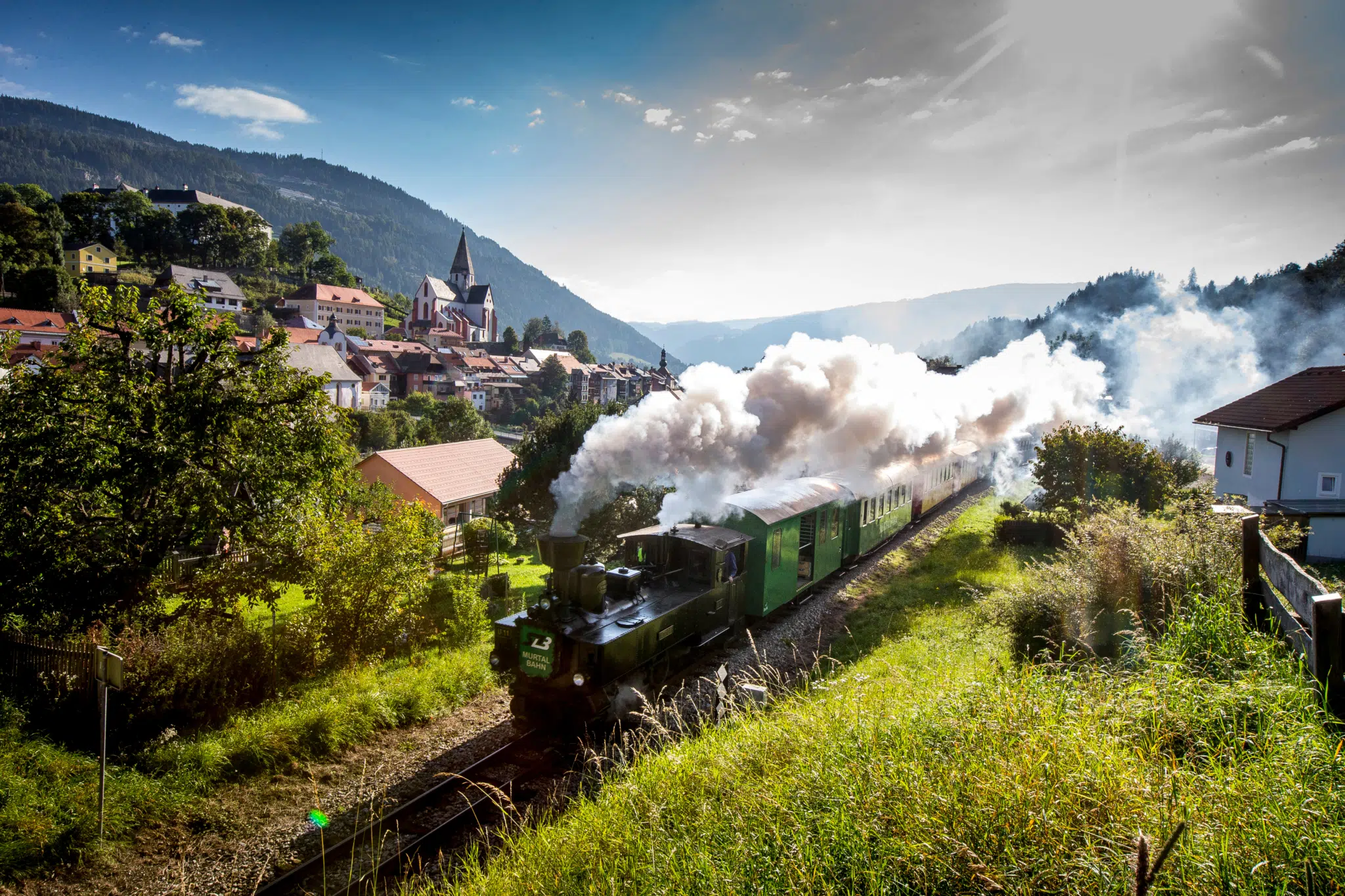 Dampfbummelzug Murtalbahn fährt in Murtal-Spielberg durch die Landschaft in der Nähe von JUFA Hotels. Der Ort für erholsamen Familienurlaub und einen unvergesslichen Winter- und Wanderurlaub.