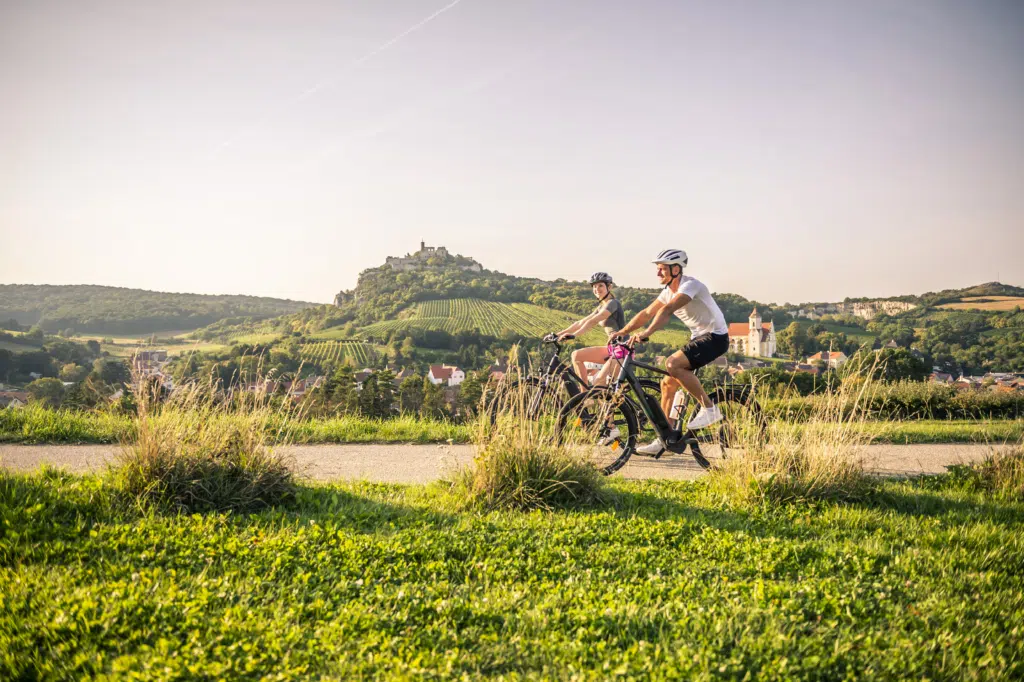 Zwei Radfahrer die genussvoll durch eine grüne Landschaft fahren.