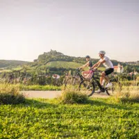 Zwei Radfahrer die genussvoll durch eine grüne Landschaft fahren.