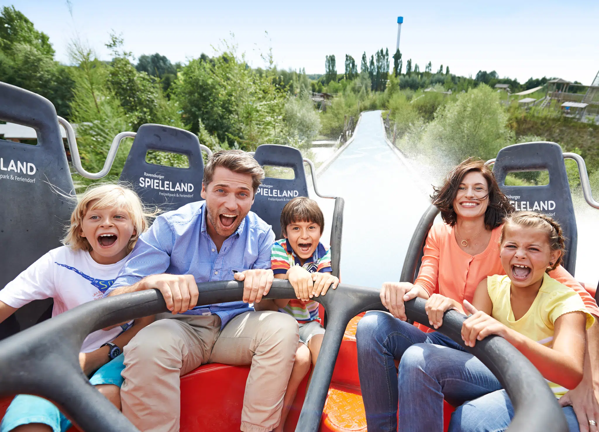 Ihr seht eine Familie beim Alpin-Rafting im Ravensburger Spieleland im Sommer nahe JUFA Hotels. Der Ort für erholsamen Familienurlaub und einen unvergesslichen Winter- und Wanderurlaub.