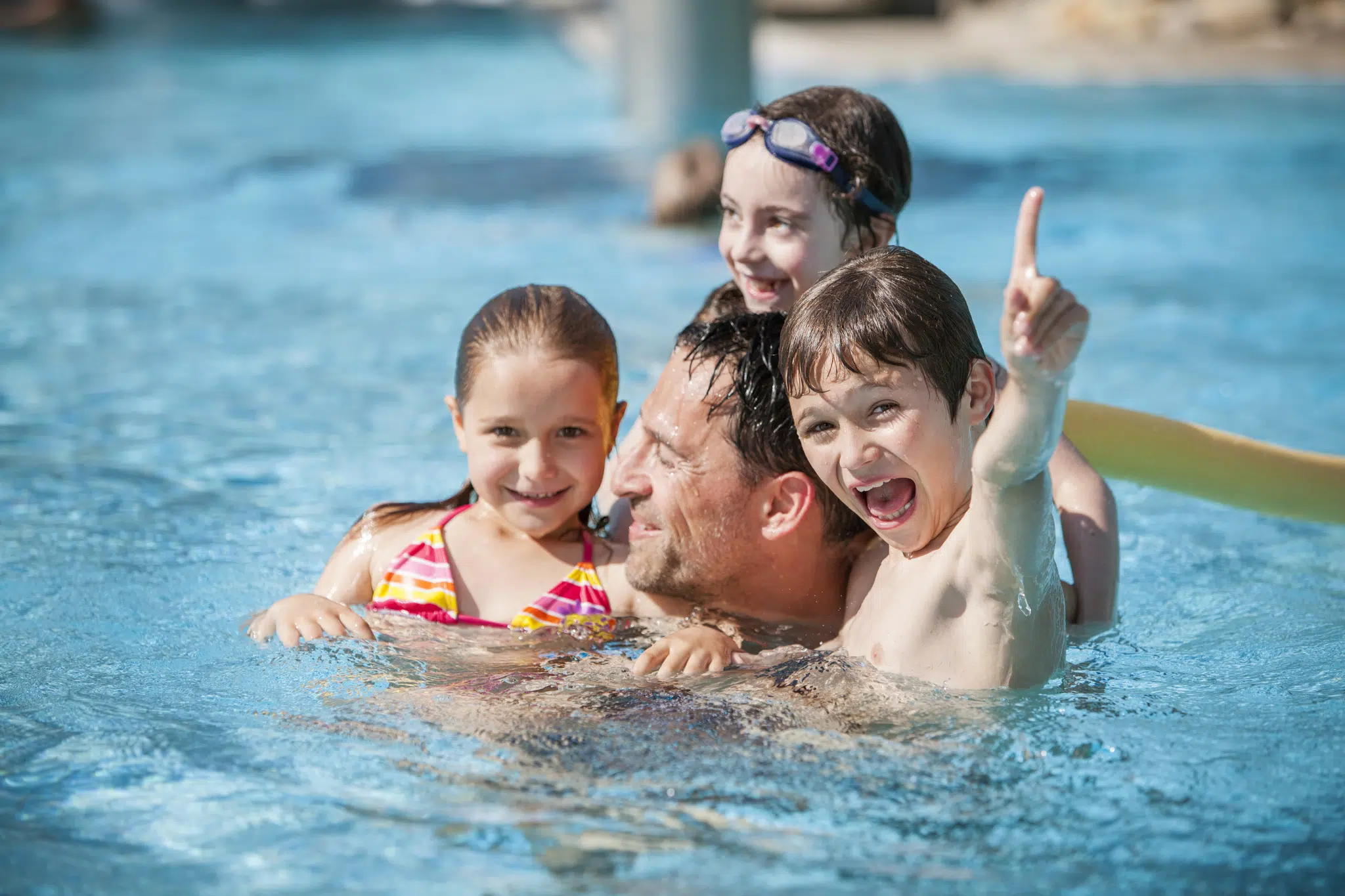 Sie sehen einen Vater mit 3 Kindern beim Schwimmen und Plantschen in der Parktherme Bad Radkersburg.