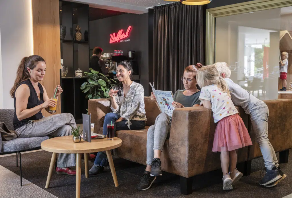 Sie sehen eine Familie mit Kindern in der Lounge im JUFA Hotel Salzburg City. Der Ort für erholsamen Familienurlaub und einen unvergesslichen Winter- und Wanderurlaub.