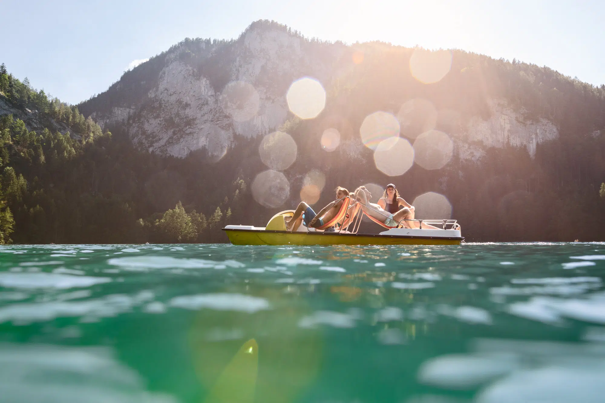 Sie sehen ein Tretboot am Gleinkersee mit Personen - unweit vom JUFA Hotel Pyhrn-Priel. Der Ort für tollen Sommerurlaub an schönen Seen für die ganze Familie.