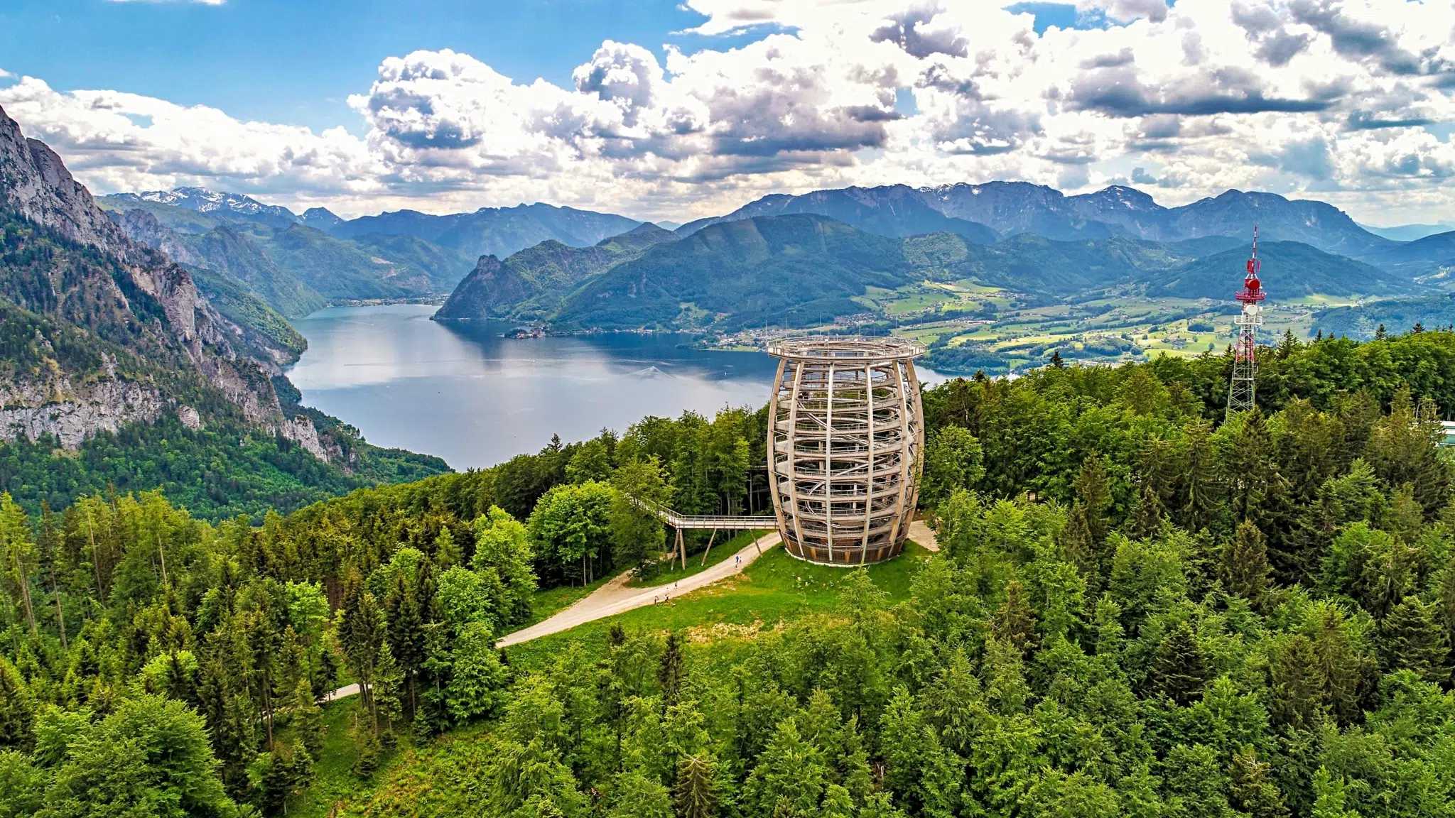 Ihr seht den Aussichtsturm des Baumwipfelpfads am Grünberg bei Gmunden mit Blick auf den Traunsee.