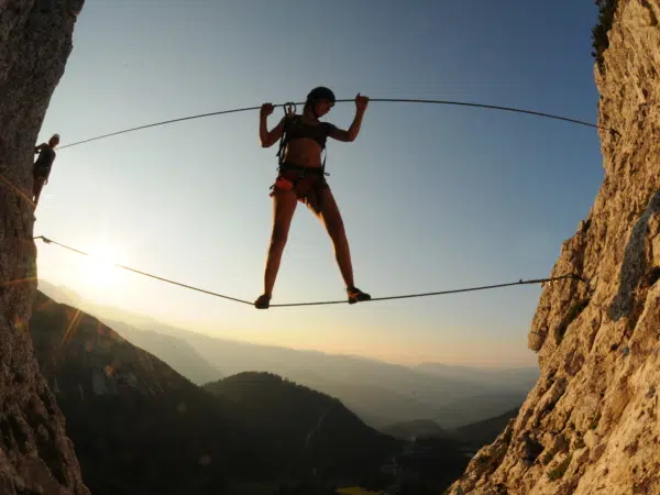 Erwachsene klettert über Schlucht am Heli-Kraft Klettersteig im Hochkar. JUFA Hotels bietet Ihnen den Ort für erlebnisreichen Natururlaub für die ganze Familie.