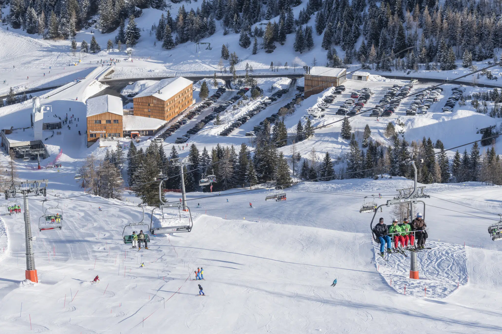 Sie sehen eine Außenansicht vom JUFA Hotel Malbun***s mit Sessellift im Winter. JUFA Hotels bietet erholsamen Familienurlaub und einen unvergesslichen Winterurlaub.