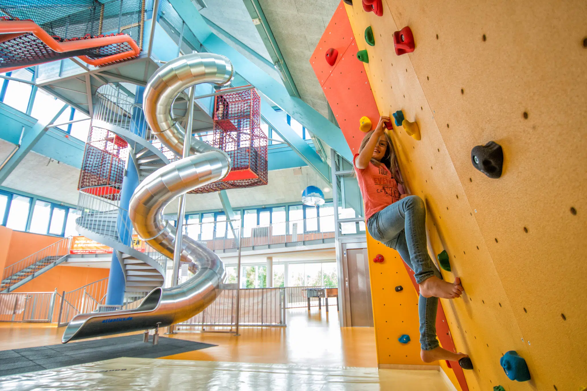 Ein Mädchen beim Klettern auf der Boulderwand im Indoorspielbereich im JUFA Hotel Jülich. JUFA Hotels bieten erholsamen Familienurlaub und einen unvergesslichen Winter- und Wanderurlaub.